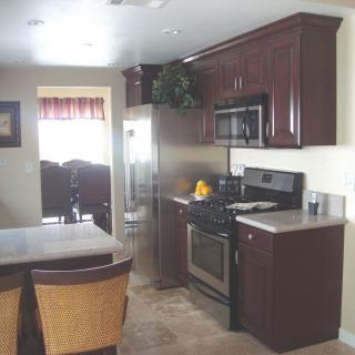 A modern kitchen with dark cabinets, stainless steel appliances, and a dining area.