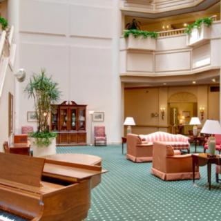 Spacious hotel lobby with elegant furniture and a grand piano.