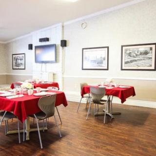 A dining area with red tablecloths, wall art, and a television.