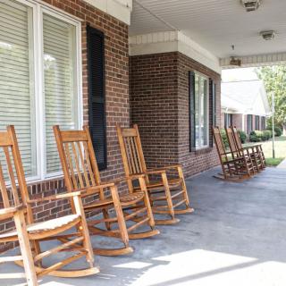 A row of wooden rocking chairs on a brick porch.