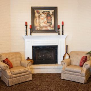 Cozy living room with a white fireplace, armchairs, and decorative elements.