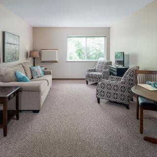 A cozy living room with neutral-colored furniture and a large window.