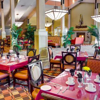 A beautifully decorated restaurant interior with neatly arranged tables and chairs, featuring elegant lighting and potted plants.