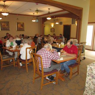 A group of seniors enjoying a meal in a dining room.