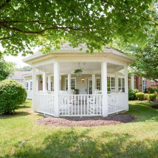 A white gazebo surrounded by a lush garden and trees.