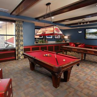 A cozy game room featuring a red-felt pool table and comfortable seating.