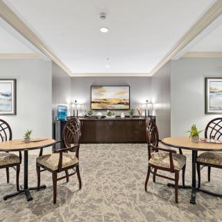 A neatly arranged seating area with tables and chairs, surrounded by elegant decor and paintings.