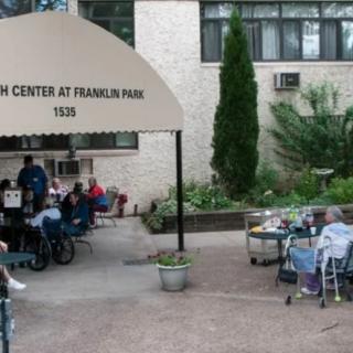 Residents gathered outside a nursing home, engaging in social activities.