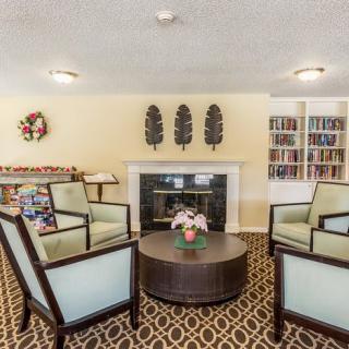 A cozy living room with armchairs around a coffee table, featuring a fireplace and bookshelves.