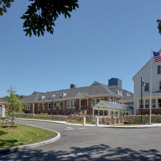 A hospital building with an American flag flying in front on a clear day.