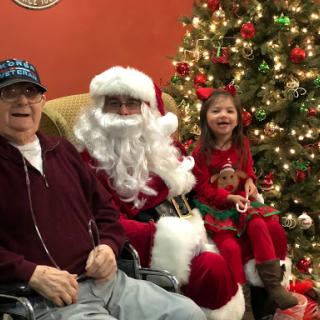 A joyful Christmas gathering with Santa Claus, a happy child, and a smiling elder.