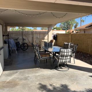 A cozy covered patio area featuring a table with chairs, a bicycle, and outdoor decor.
