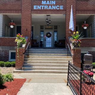 Main entrance of a brick building with decorative flower pots and a welcoming atmosphere.
