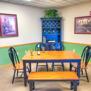 A cozy dining room with a wooden table set, blue hutch, and decorative paintings.