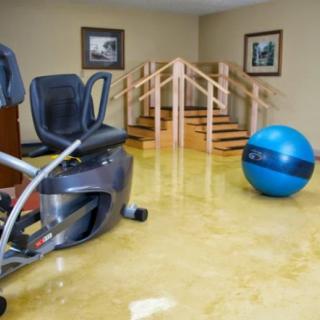 A rehabilitation room equipped with a recumbent bike, fitness ball, and parallel bars for physical therapy exercises.