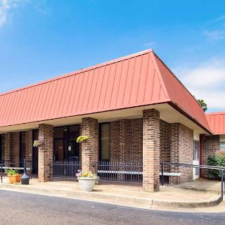 A well-maintained commercial building featuring a striking red metal roof and brick exterior.