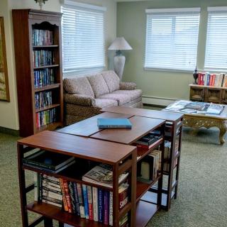 A cozy library room with bookshelves, a sofa, and a table.