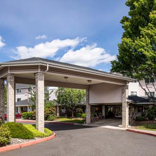 A hotel entrance with a covered driveway surrounded by trees and landscaping.