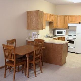 A small kitchen with wooden cabinets and a dining table set.