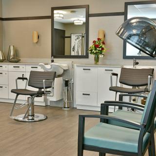 A modern hair salon with styling chairs, large mirrors, and a hooded hair dryer.