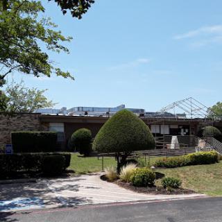 A well-maintained building surrounded by greenery and a clear blue sky.
