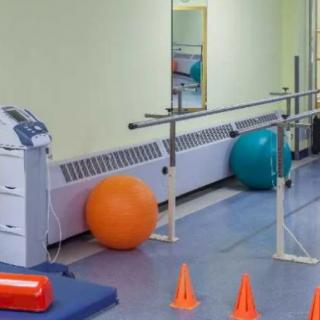 A physical therapy room equipped with balance bars, exercise balls, and cones.