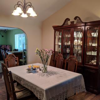 A cozy dining room with a wooden table, matching chairs, and a china cabinet.