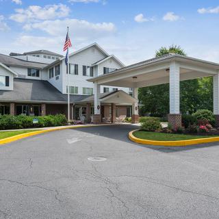A residential or hotel building with a covered entrance and well-maintained landscaping on a cloudy day.