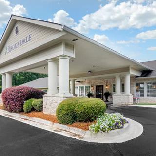 The entrance of a building with landscaped shrubs and a paved driveway.