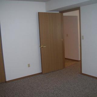 An empty room with carpet flooring and open doors.