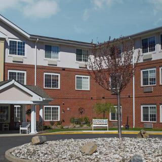 A multi-story brick and siding residential building with landscaped surroundings.