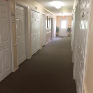 A well-lit indoor hallway lined with white doors.