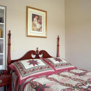 A cozy bedroom featuring a quilted bed with matching pillows and a decorative framed artwork above the headboard.