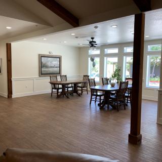 A spacious dining area with wooden floors and large windows allowing natural light to flood the room.