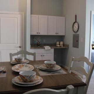 A cozy dining area with a table set for four, adjacent to a small kitchenette.