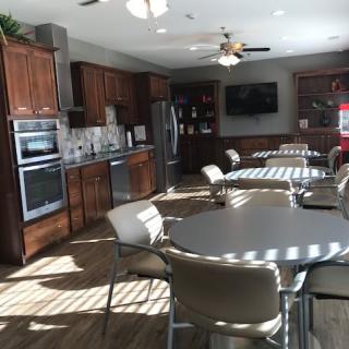 A modern kitchen and dining area with wooden cabinets and multiple tables and chairs.