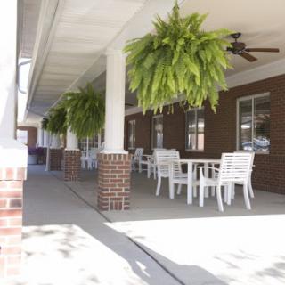 A serene outdoor porch area adorned with hanging plants and white furniture.