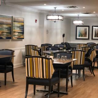 A modern dining area with striped chairs, tables, and decorative artwork on the walls.