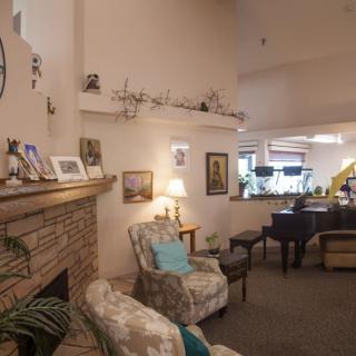 A cozy living room featuring a fireplace, armchair, and grand piano.