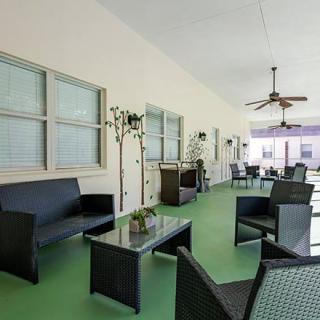 A spacious outdoor patio area with seating, tables, ceiling fans, and decorative plants.