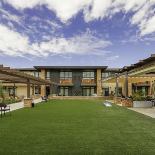 A modern building with a central courtyard and well-maintained lawn under a partly cloudy sky.