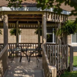 A cozy gazebo with outdoor seating, providing a shaded area in a garden setting.