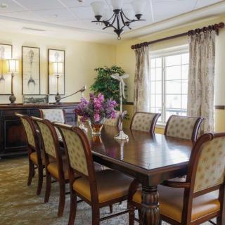 A well-decorated dining room featuring a large table, elegant chairs, a chandelier, and a window with curtains.