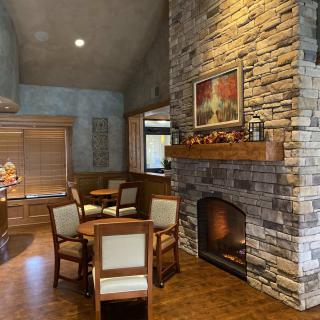 A cozy living room with a stone fireplace, wooden furniture, and a painting above the mantel.