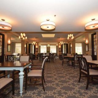 A spacious dining room with elegant chandeliers, tables, and chairs arranged neatly.
