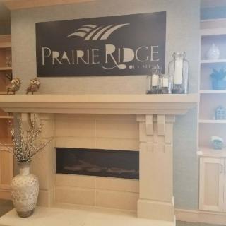 A cozy fireplace with a 'Prairie Ridge' sign above it, surrounded by decorative elements.