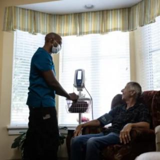 A healthcare professional attends to an elderly patient in a home setting.