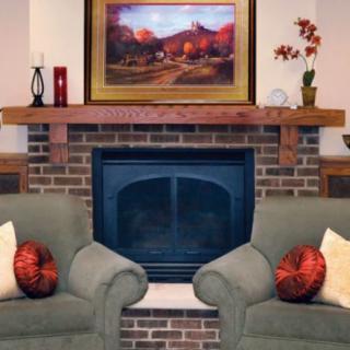 A cozy living room with a brick fireplace, armchairs, and decorative elements.