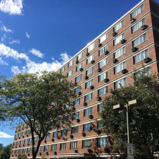A residential apartment building with a clear blue sky and surrounding trees.