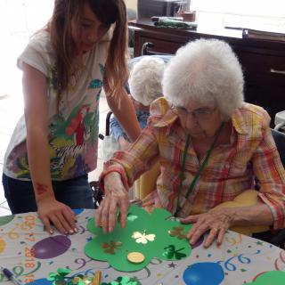 An elderly woman and a young girl engaged in a crafting activity together.